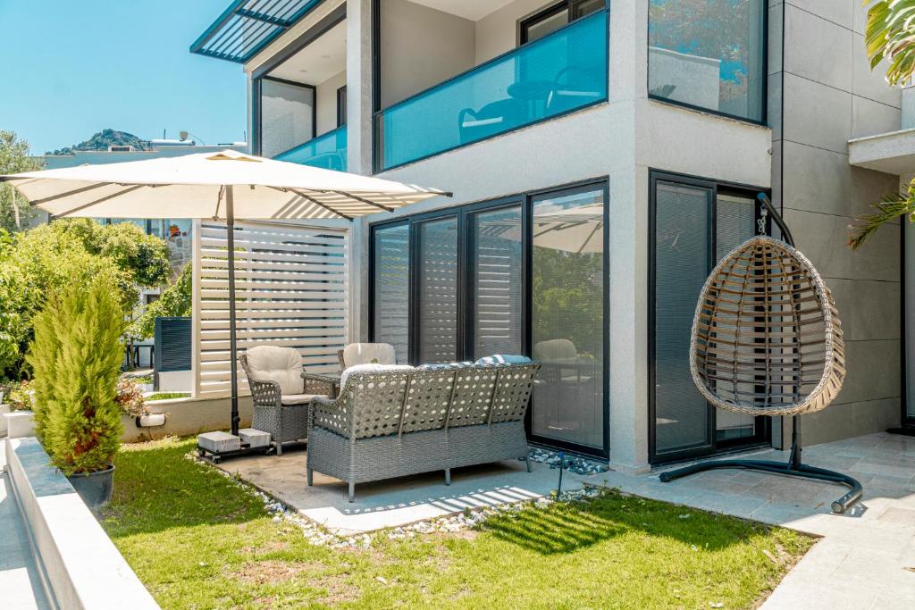 Casa con patio con sombrilla y sillas en Yalikavak Superior Duplex Villa en Bodrum