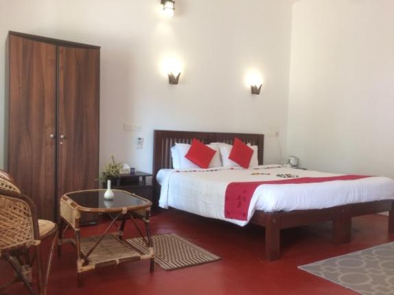 - une chambre avec un lit doté d'oreillers rouges et d'une table dans l'établissement Leena marari beach house, à Alappuzha
