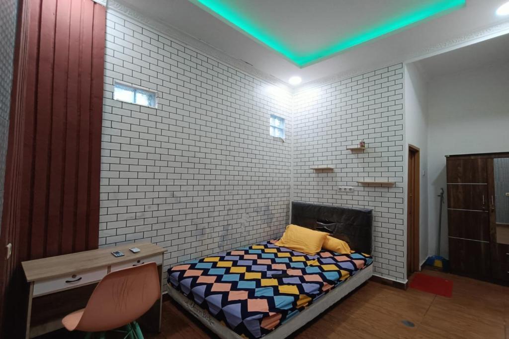 a bedroom with a bed and a brick wall at OYO Life 93158 Kost Asaka in Serang