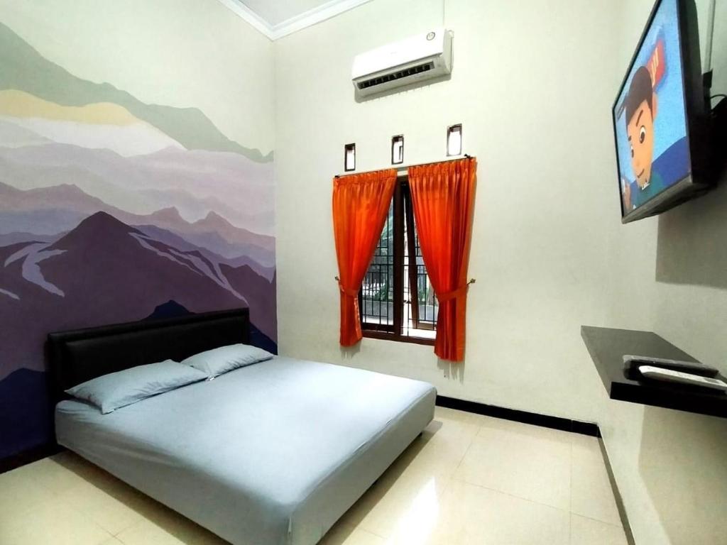 a bedroom with a bed and a tv and a mural at Mamora Guest House in Kalasan