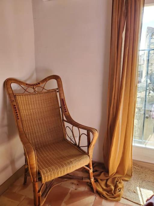 a wicker chair sitting in front of a window at Le Bohème in Sigean
