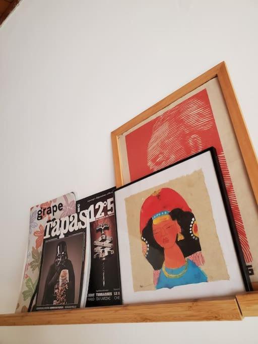 a shelf with books and a picture of a woman at Le Bohème in Sigean