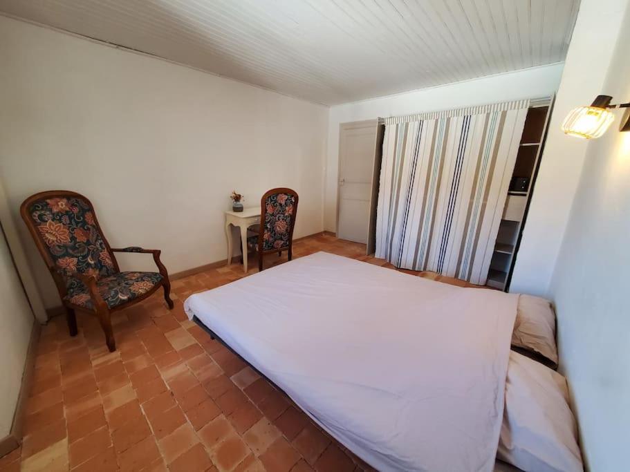 a bedroom with a white bed and two chairs at Le Bohème in Sigean