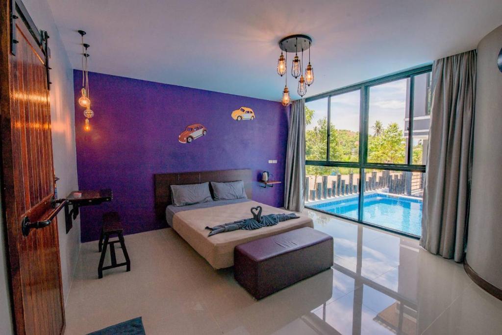 a bedroom with a purple wall and a bed and a pool at Angela resort in Ban Benyaphat