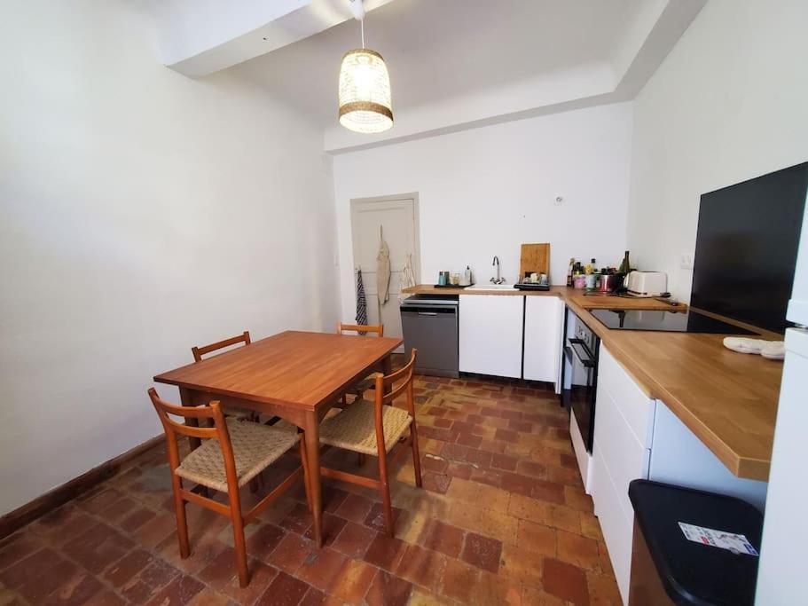 a kitchen with a wooden table and chairs in it at Le Bohème in Sigean