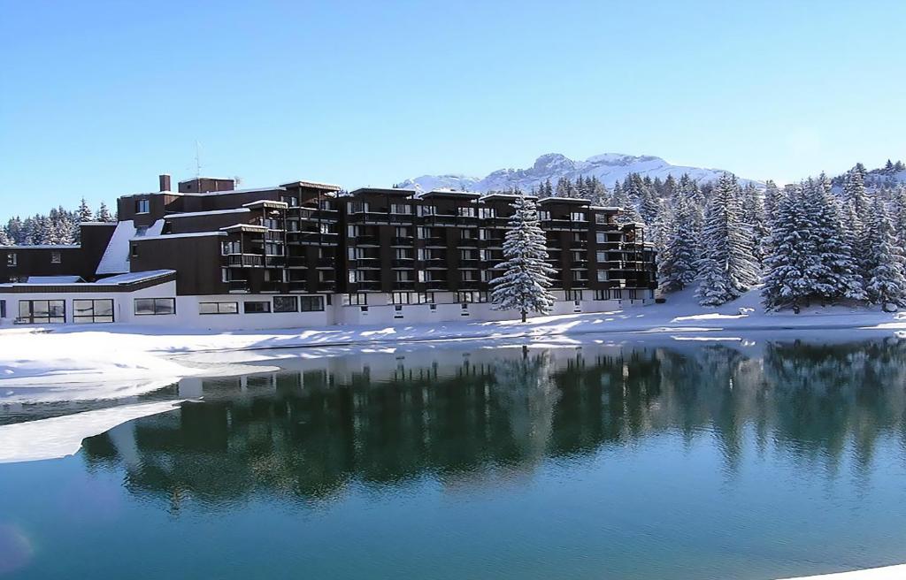 um hotel na neve ao lado de um lago em Lake Hotel Courchevel 1850 em Courchevel