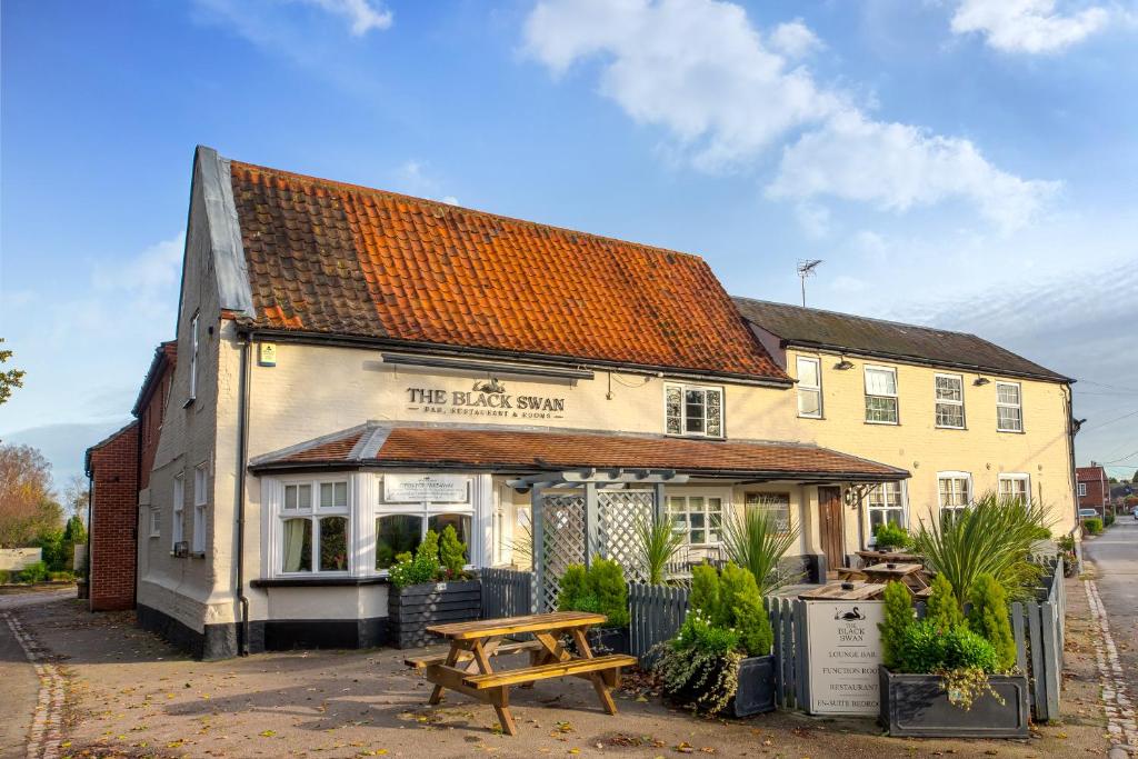 un edificio con una mesa de picnic delante de él en The Black Swan Inn en Norwich