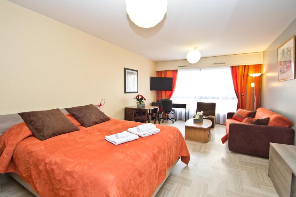 une chambre avec un grand lit orange et un salon dans l'établissement GRAY 2a6, à Cannes