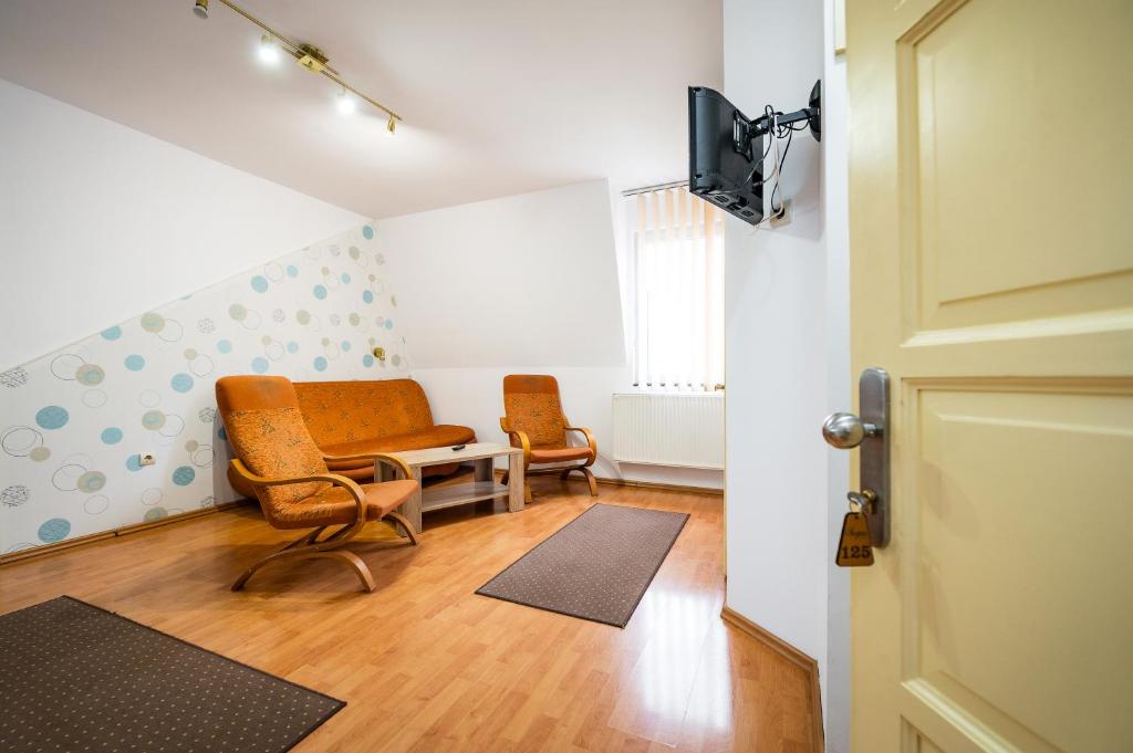 uma sala de estar com duas cadeiras e uma televisão em Hotel Sugas em Sfântu Gheorghe