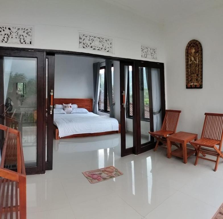 a bedroom with a bed and two chairs at Giri Swari Homestay in Sidemen
