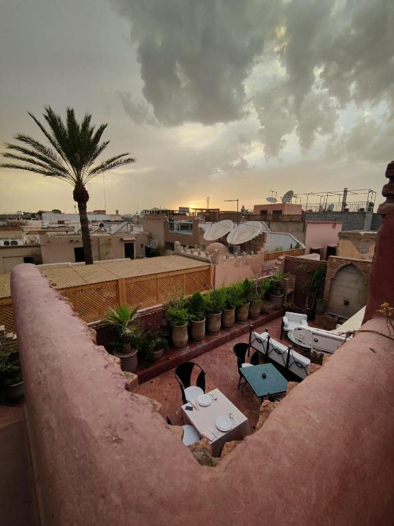 a balcony with tables and chairs and a palm tree at Riad Assalam in Marrakech