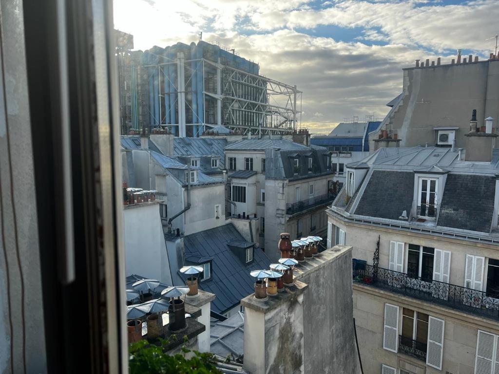 une vue depuis une fenêtre sur les toits des bâtiments dans l'établissement Appartement - Belle vue - Marais, à Paris