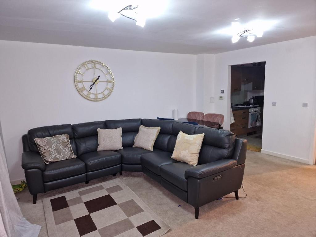 un divano nero in un soggiorno con un orologio sul muro di KO 3 bed house a Kent