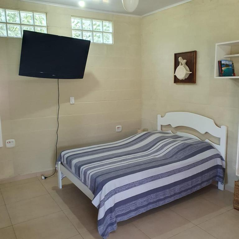 a bedroom with a bed and a flat screen tv at Casinha Mar e Sol Boiçucanga in São Sebastião