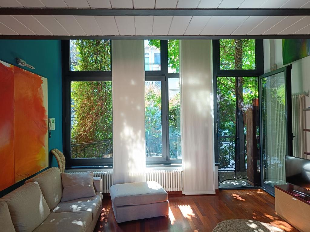 salon z kanapą i dużymi oknami w obiekcie Loft Certosa District con parcheggio privato w Mediolanie