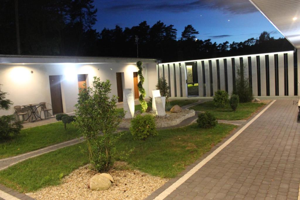 une maison la nuit avec un arbre dans la cour dans l'établissement Oaza, à Turawa