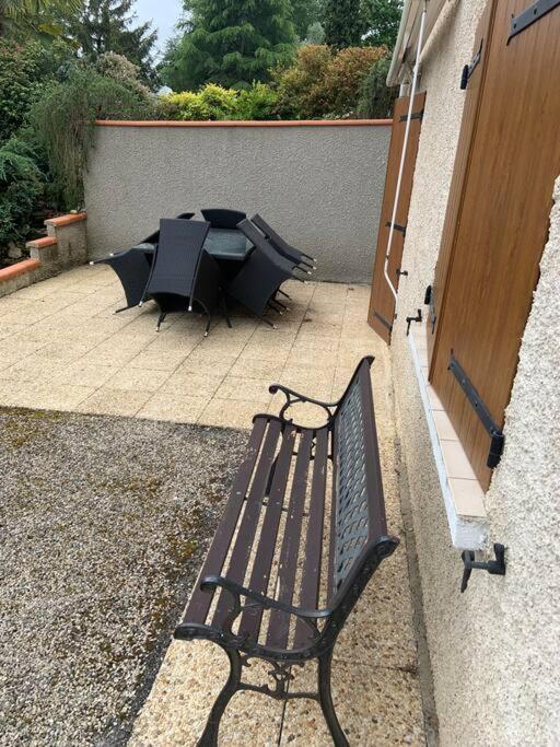 un banco negro sentado junto a una mesa con un paraguas en Maisonnette 1 chb à la campagne, en Eauze