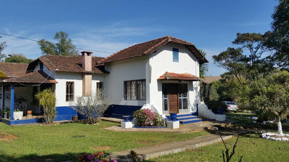 een wit huis met een tuin bij Pousada Sino dos Ventos in São Sebastião do Rio Verde