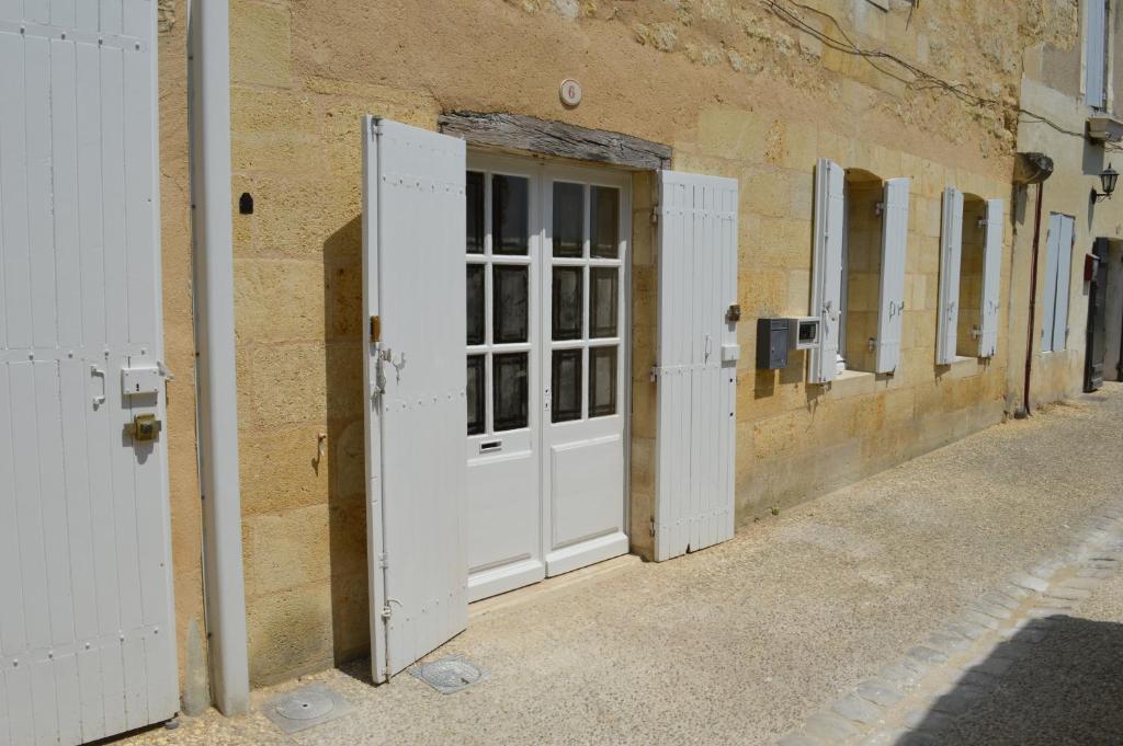 a white door on a brick building with windows at Logis des Jurats in Saint-Émilion