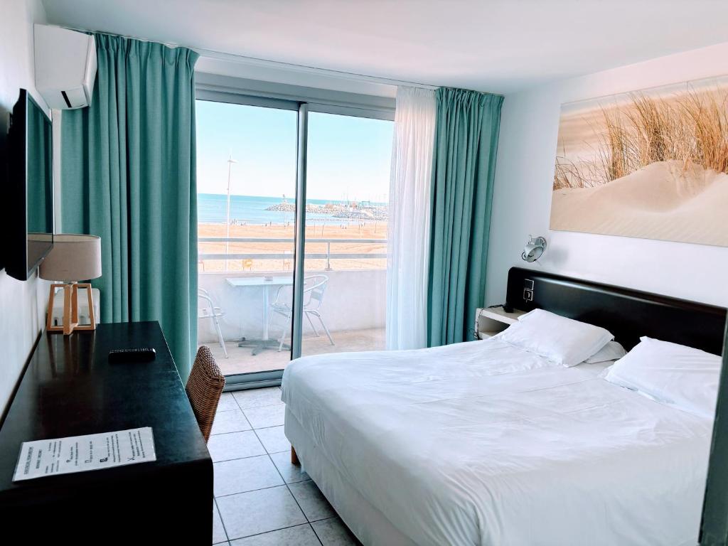 um quarto de hotel com uma cama, uma secretária e uma janela em Brasilia Hôtel em Palavas-les-Flots