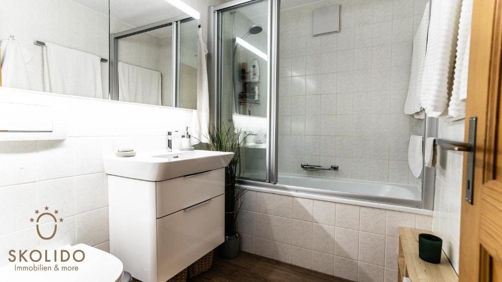 a white bathroom with a sink and a tub at Wohnung Gomerblick, Blitzingen in Blitzingen