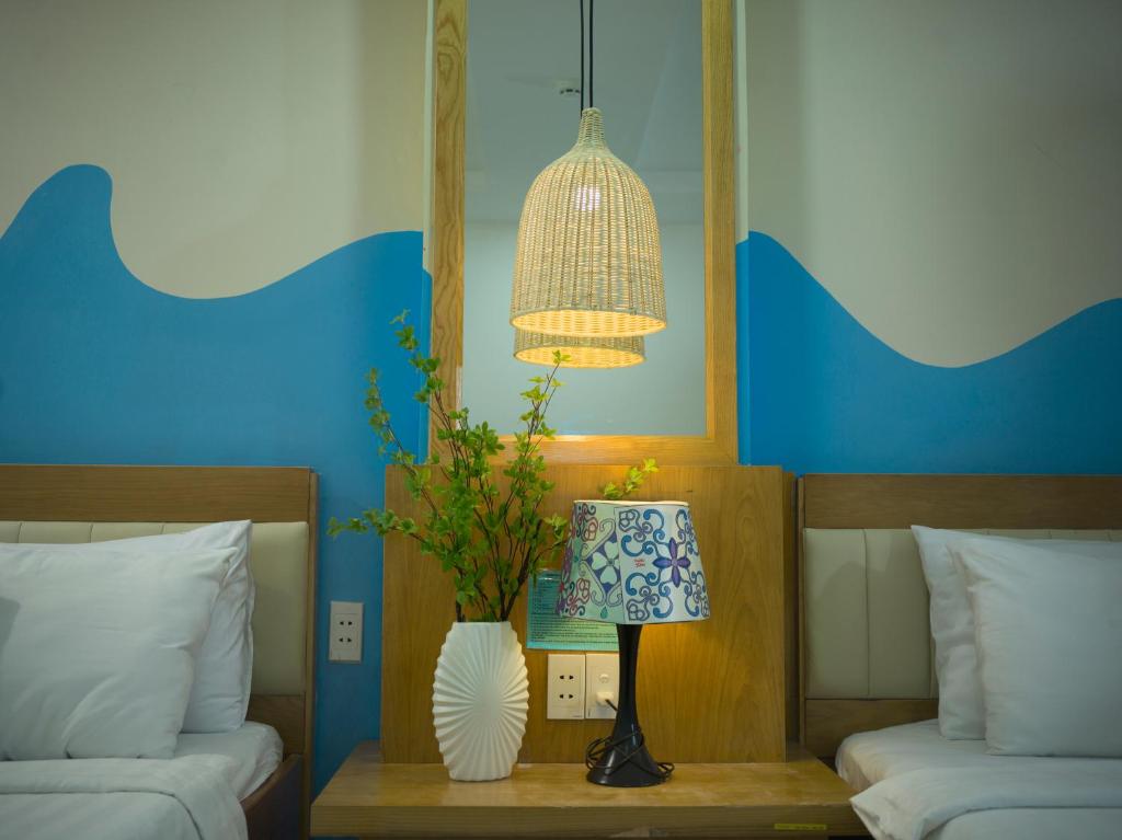 a room with two beds and a lamp with a vase at Summer Beach Hotel Vung Tau in Vung Tau