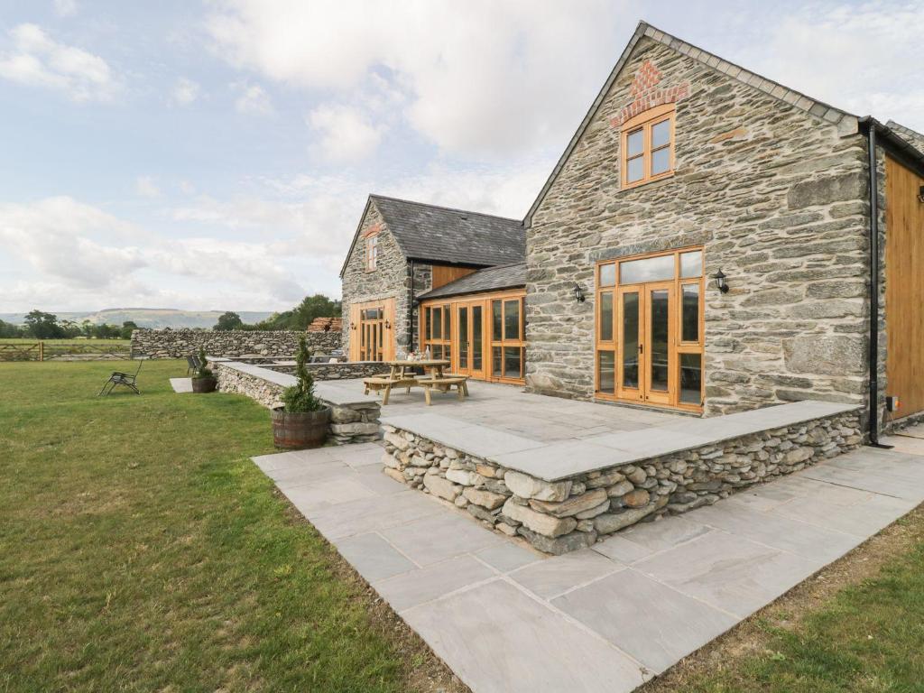 una casa in pietra con un tavolo da picnic di fronte di The Barn a Corwen