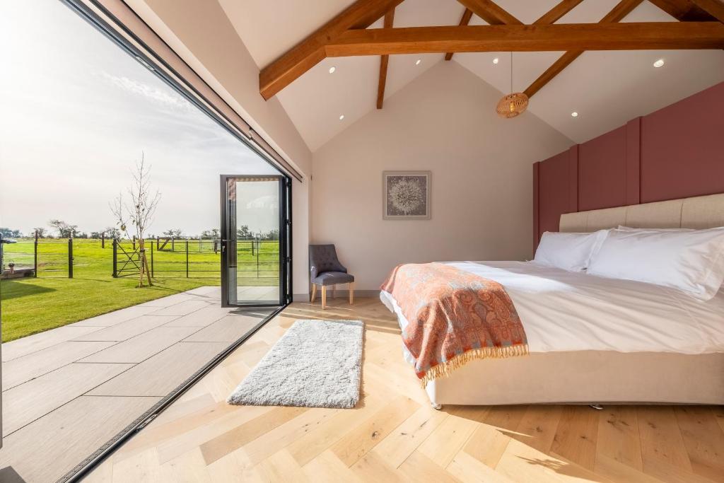 a bedroom with a bed and a large window at Large immaculate rural conversion - The Milking Parlour in Ipswich