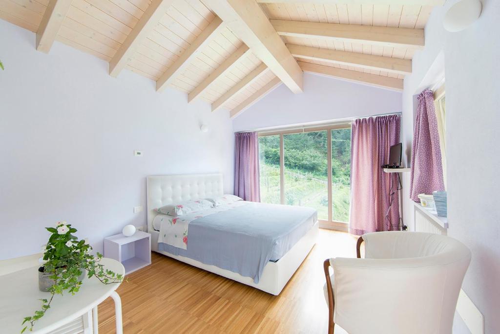 a white bedroom with a bed and a table and chairs at Agriturismo Rossolampone in San Bernardino Verbano