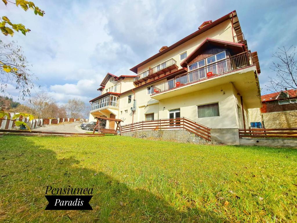 una casa con un césped verde delante de ella en Pensiunea Paradis en Buşteni