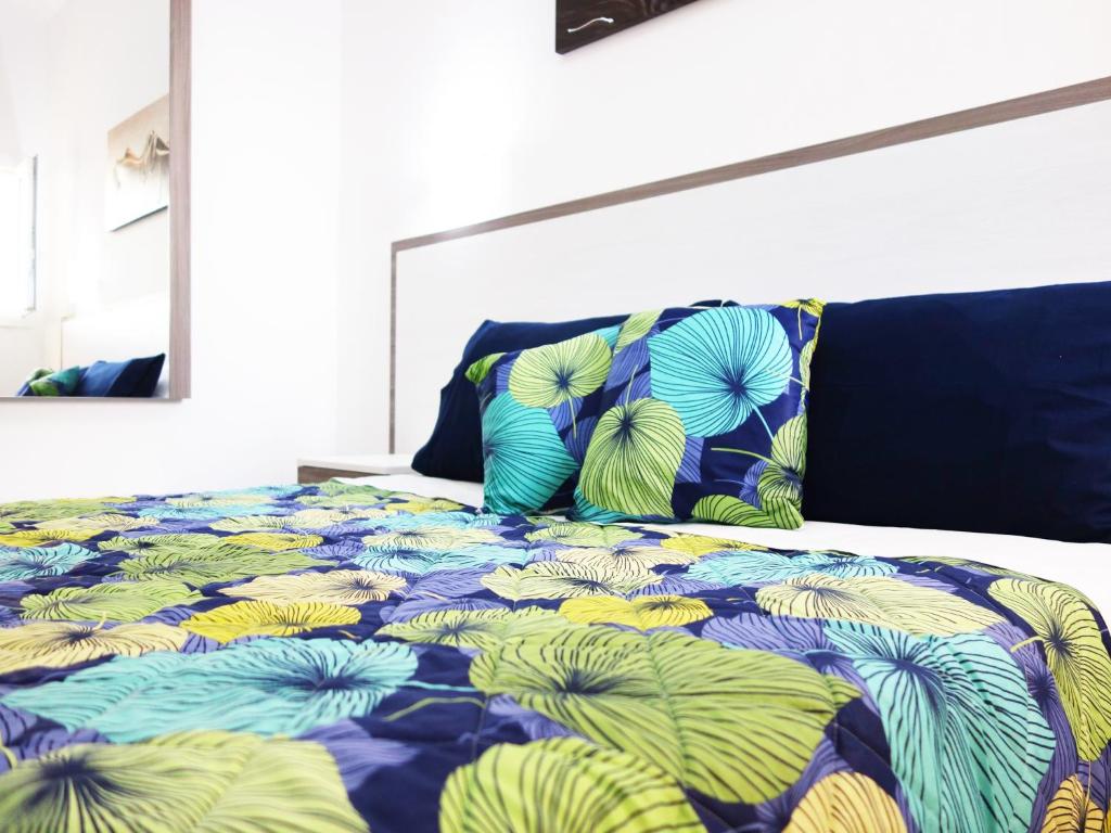 Bett mit einer blauen und grünen Bettdecke und Kissen in der Unterkunft L'insenatura in Torre Lapillo