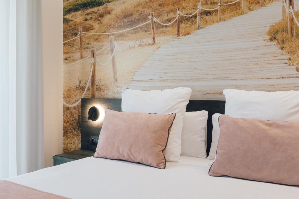 a bed with pillows and a painting of a boardwalk at Palau Apartments Valencia in Valencia