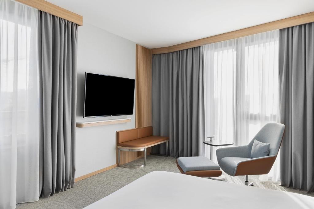 Habitación de hotel con cama, TV y silla en Courtyard by Marriott Biel Bienne, en Biel