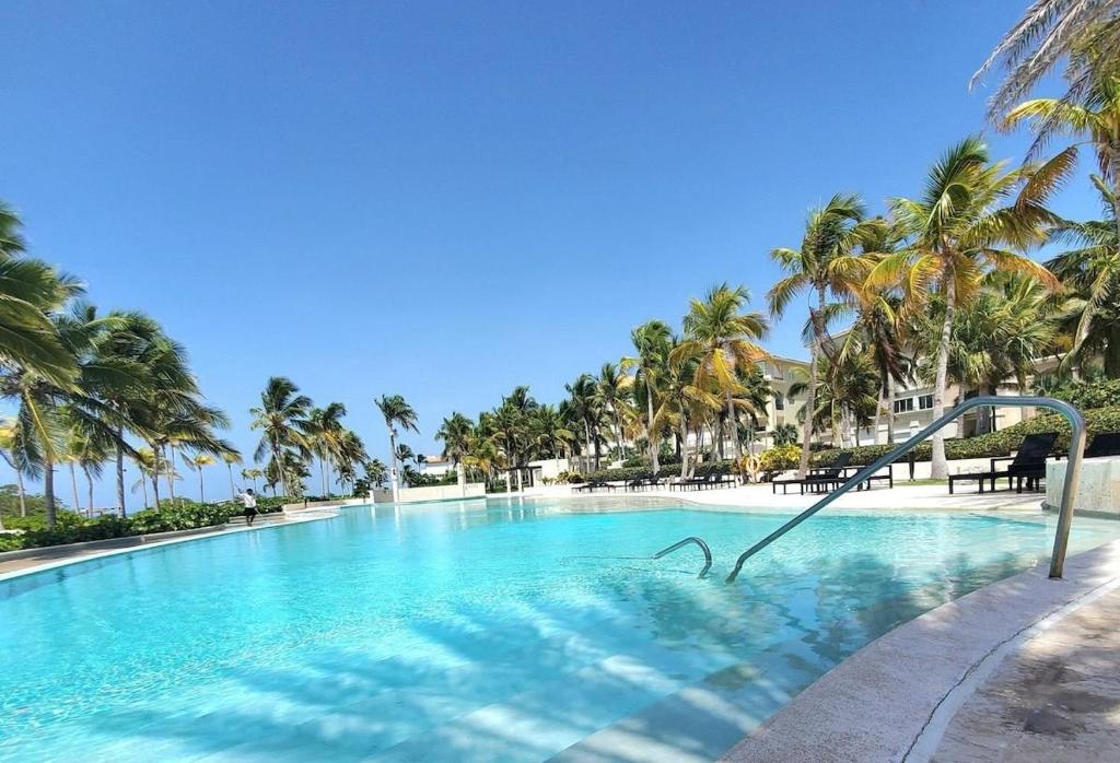 una piscina con palmeras y un tobogán en Hermoso y perfecto 2 Hab frente al mar en Cap Cana en Punta Cana