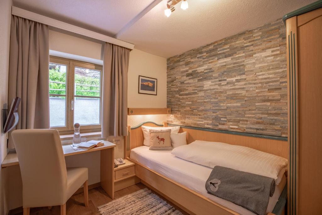 1 dormitorio con cama y pared de ladrillo en Patteriol Apart-Hotel-Garni en Sankt Anton am Arlberg