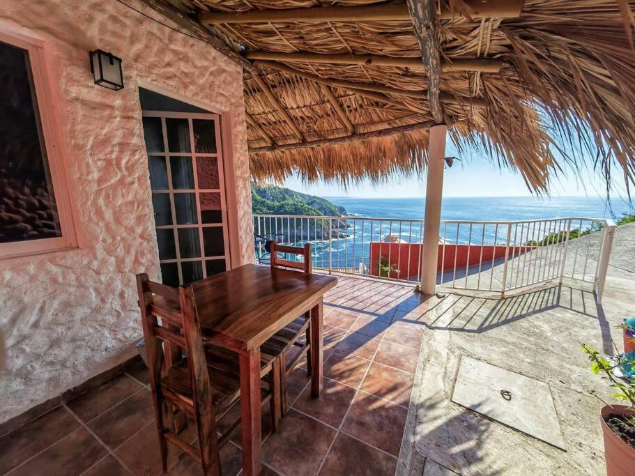 een eetkamer met een tafel en uitzicht op de oceaan bij Bungalow Maya Luna in Playa Estacahuite