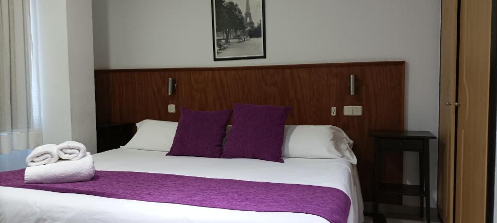 Un dormitorio con una cama grande con sábanas y almohadas púrpuras. en Hostal Doña Isabel, en Majadahonda