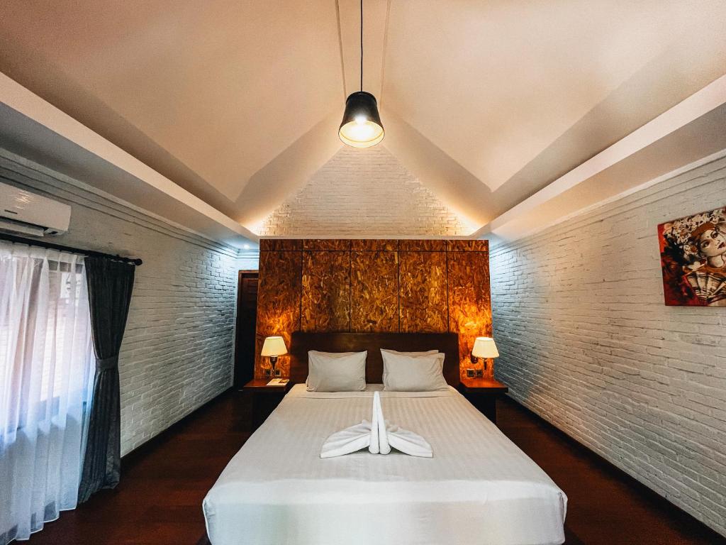 a bedroom with a large white bed with two white towels on it at Uma Mani Villa Bali in Jimbaran