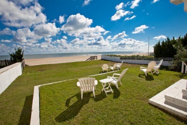 a group of chairs sitting on the grass near the beach at Shoreline Cottage - Oceanfront - North End VB in Virginia Beach