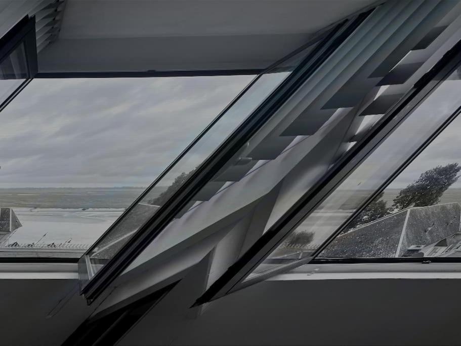 a window in a building with a view of the water at Le Belvédère de la Baie, grand gîte pour deux in Saint-Valéry-sur-Somme