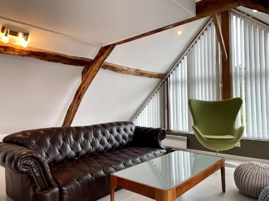 a living room with a leather couch and a green chair at Le Belvédère de la Baie, grand gîte pour deux in Saint-Valéry-sur-Somme