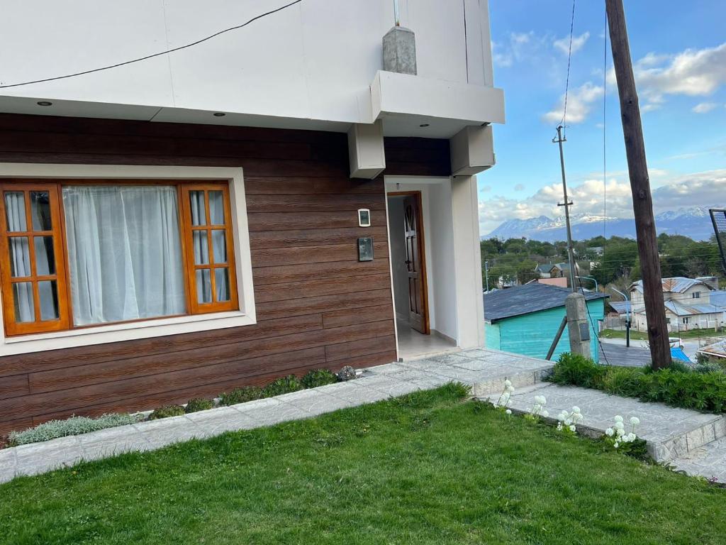 a house with a window and a grass yard at Ushuaia_aparts Depto 1 in Ushuaia