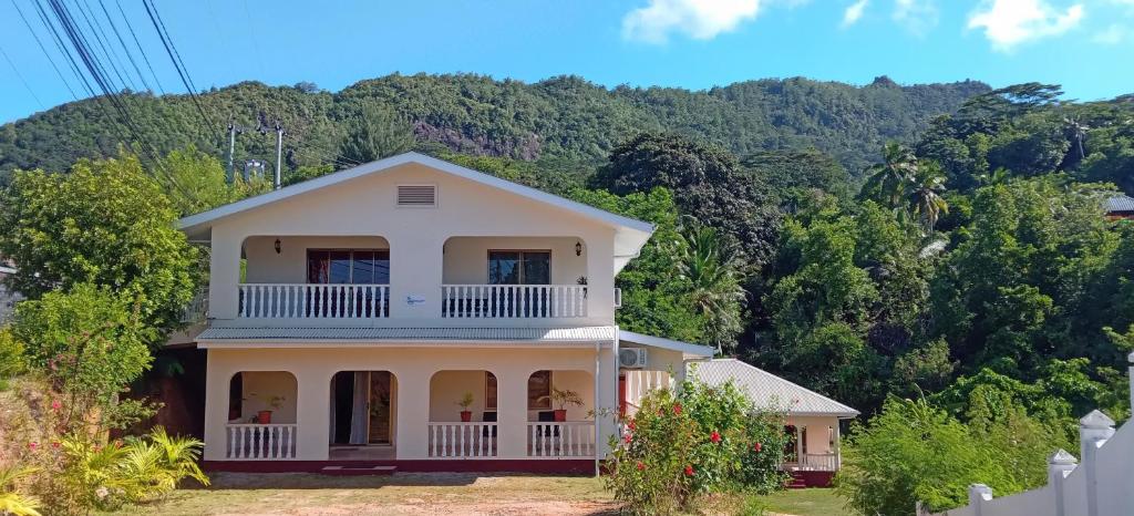 a house in front of a mountain with trees at L’échappée du Cap in Mahe