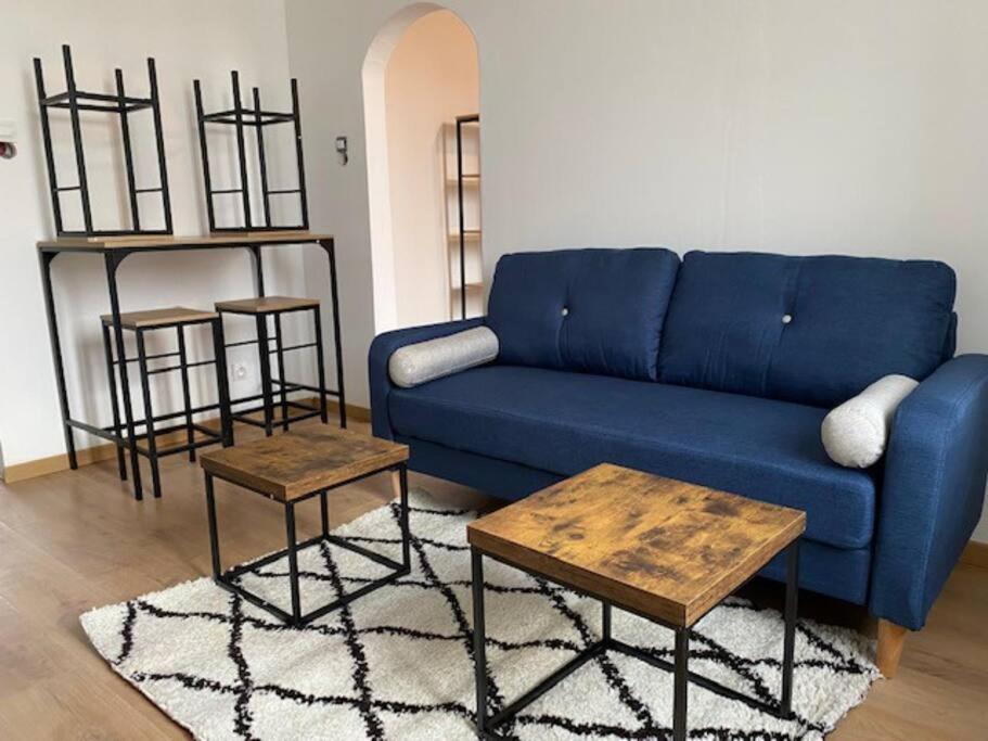 ein Wohnzimmer mit einem blauen Sofa und 2 Tischen in der Unterkunft Appartement Cosy T3 - 2 chambres in Le Creusot