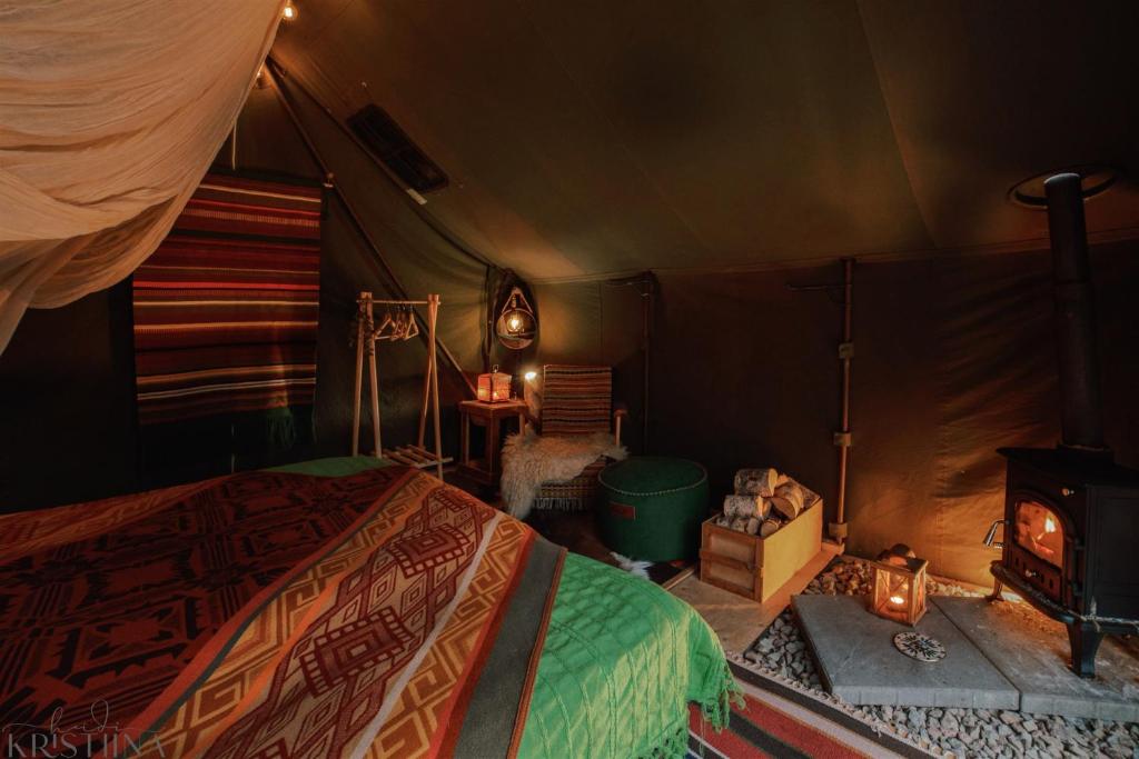 1 Schlafzimmer mit einem Zelt mit einem Bett und einem Kamin in der Unterkunft Ainutlaatuinen metsämajoitus in Enontekiö