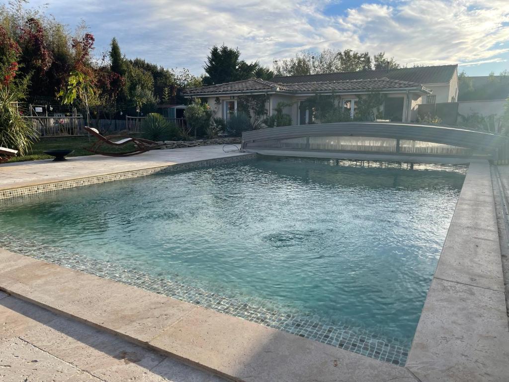 a swimming pool with a bridge in front of a house at Pavillon T2 climatisé in Villefranche-de-Lauragais