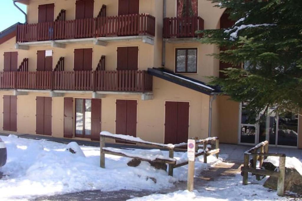 un bâtiment avec des portes brunes et de la neige devant lui dans l'établissement Studio Cabine Ax Les 3 Domaines, à Ax-les-Thermes