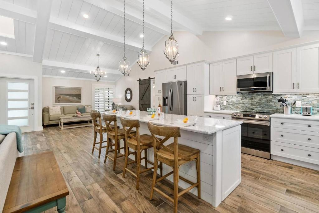 a kitchen with white cabinets and a large island with bar chairs at Tahiti Cottage in Marco Island