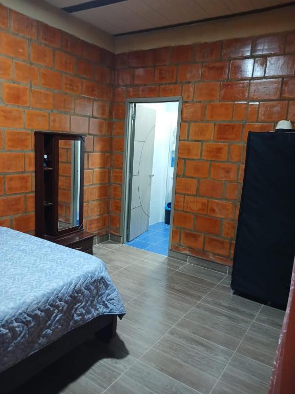 a bedroom with a bed and a brick wall at Casa Girardot in Tocaima