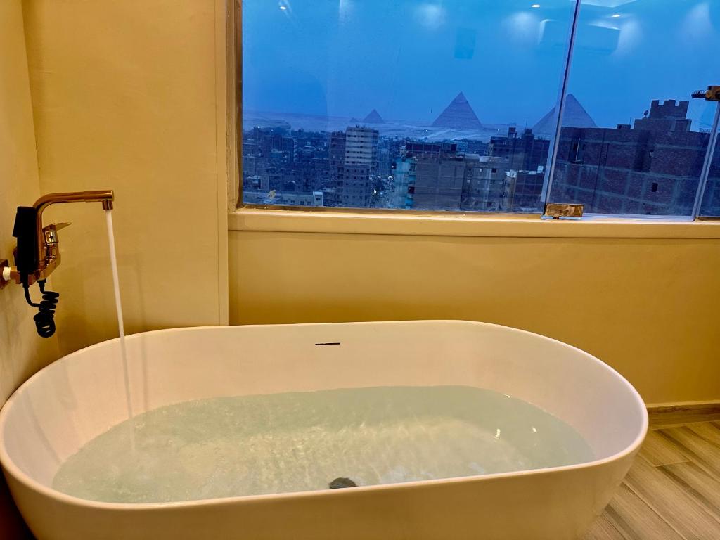 y baño con bañera y ventana. en pyramids guest house en El Cairo